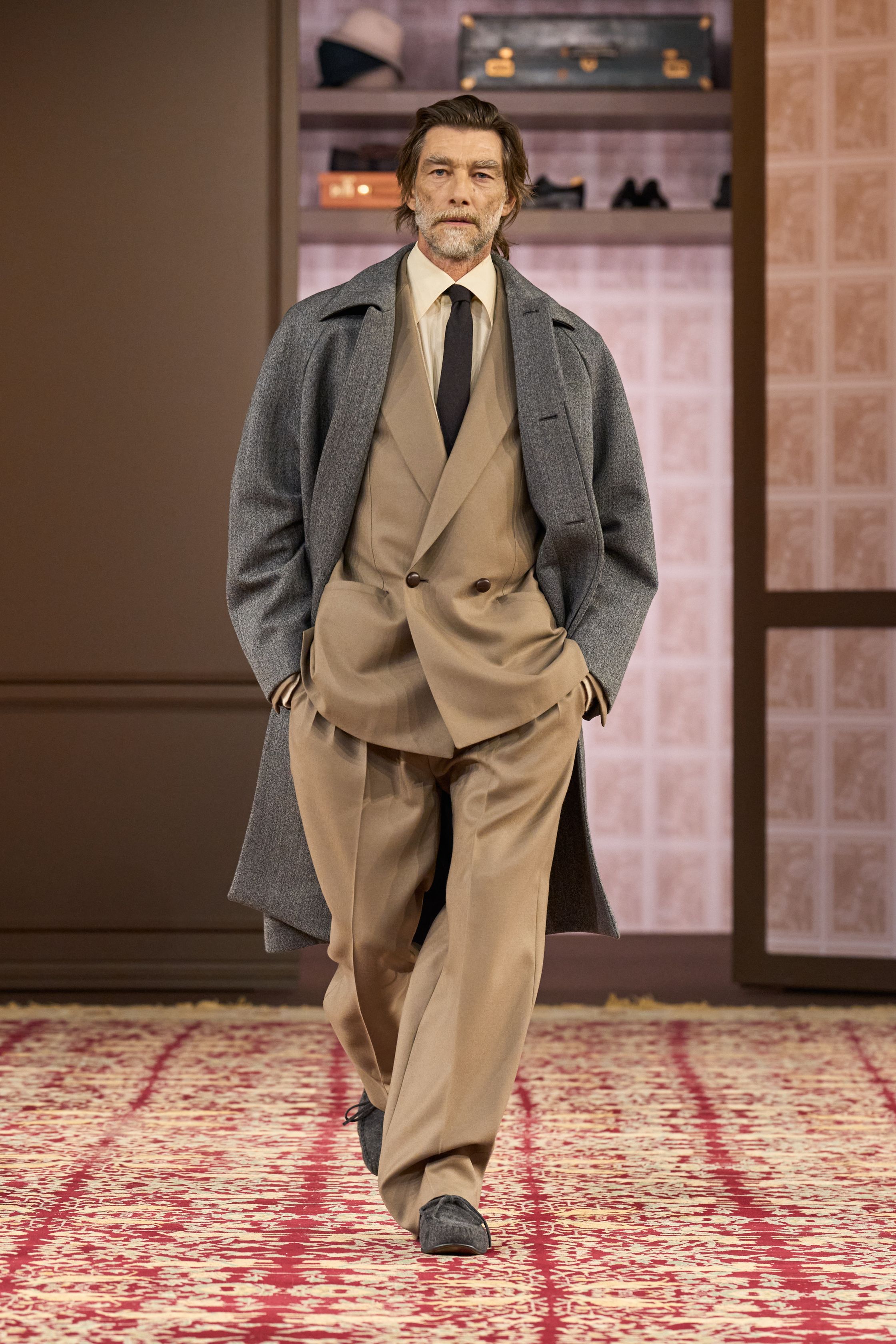 ZEGNA 2026秋冬以“安静权威”为核心命题，在高度私密、近乎沙龙式的空间中重塑当代男性精英形象。柔和灯光下，西装、大衣与针织被处理得异常克制，廓形松弛却精准，强调肩线的自然下垂与裤装的流动垂感。羊毛、羊绒与精纺面料成为绝对主角，色彩集中于驼色、烟灰、深橄榄与夜黑，传递一种无需证明的自信。这一季ZEGNA不谈趋势，而是提出一种长期有效的男性着装秩序——成熟、内敛、经得起时间审视的“当代绅士体系”-顽石频道趋势研究